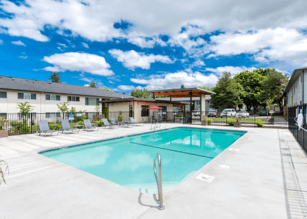 The Groves swimming pool area with lounge chairs and covered pergola