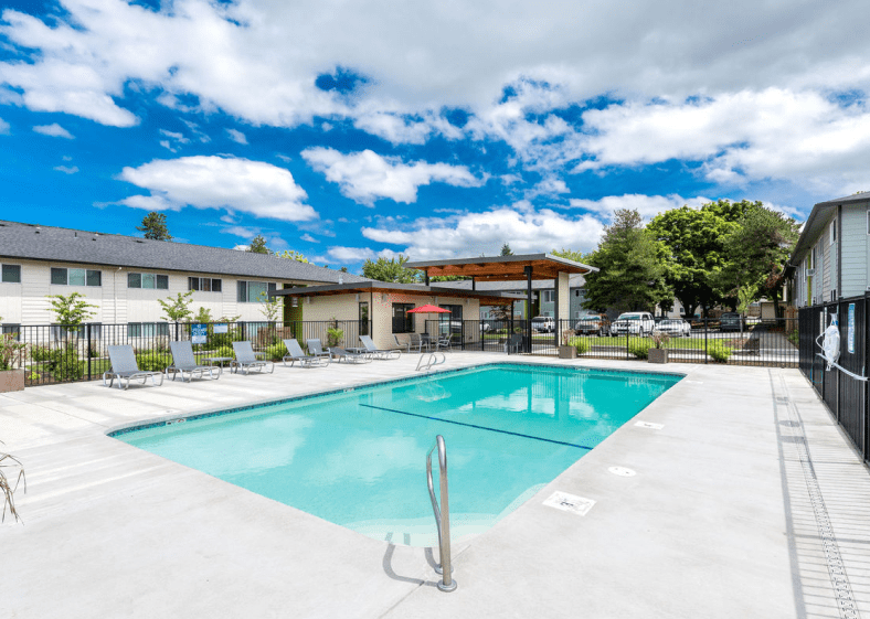 The Groves swimming pool area with lounge chairs and covered pergola area