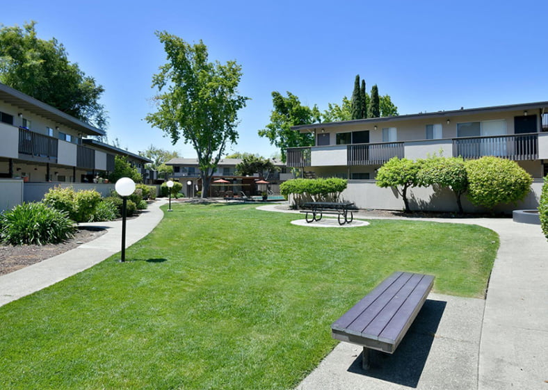 Jackson Flats Apartments exterior common area with sidewalks and picnic bench