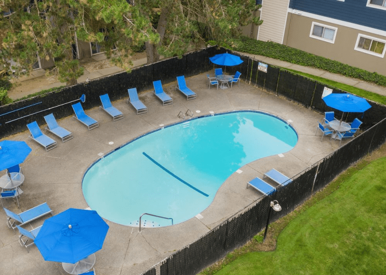 Renton Sage swimming pool area with lounge chairs, tables, and umbrellas
