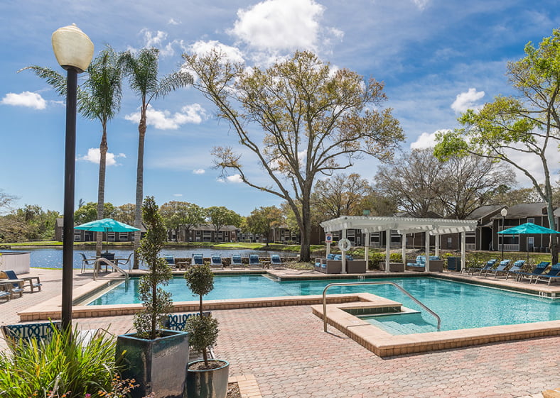 Apartment complex pool area located near pond